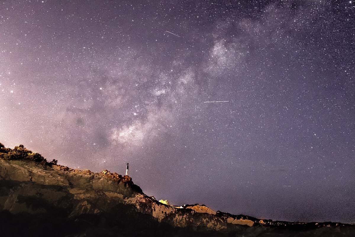 night person standing on rock formation under starry sky astronomy